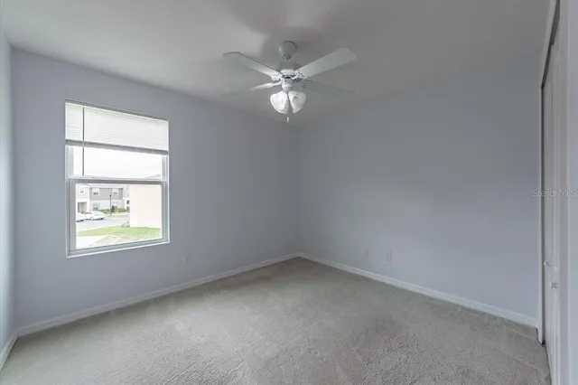 an empty room with a window and a fan