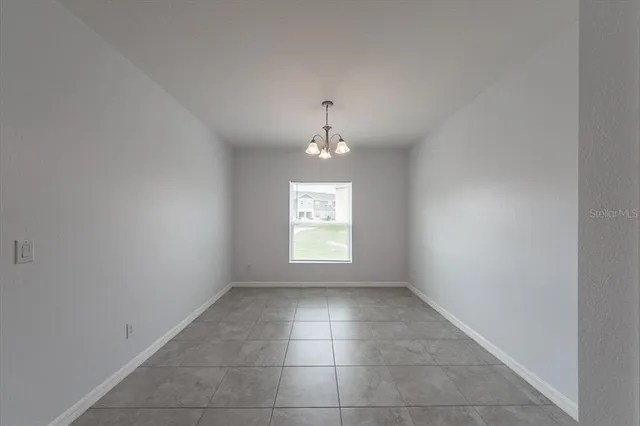 an empty room with a chandelier and a window