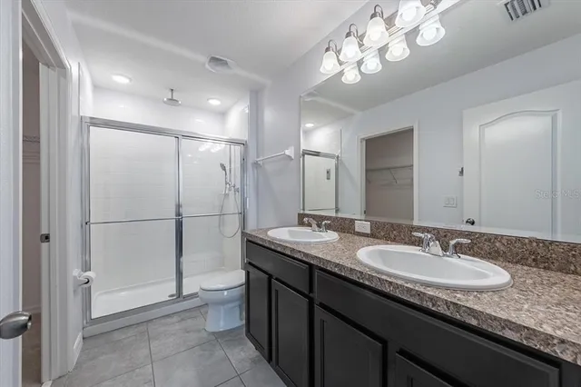 a bathroom with a granite countertop sink a toilet a mirror and shower
