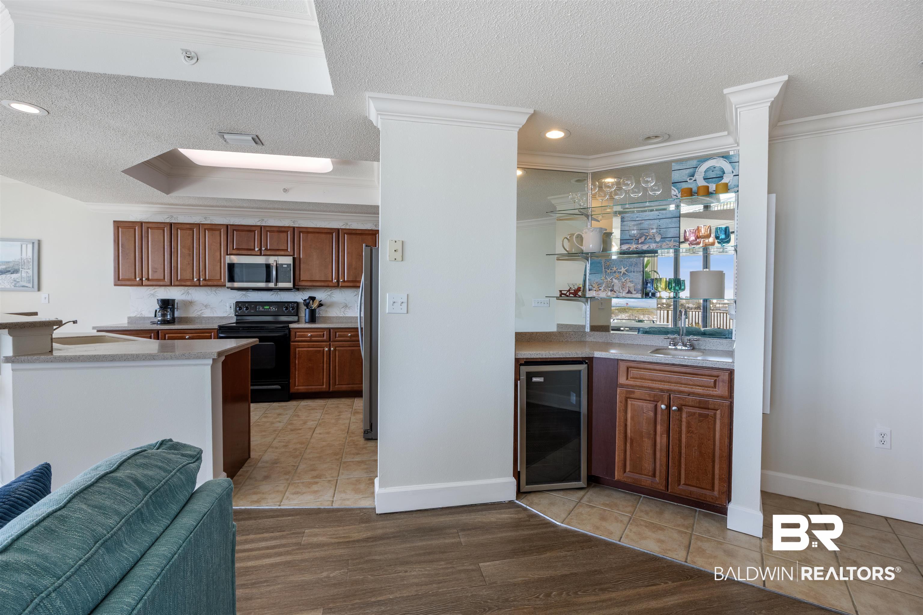 27580 Canal Road, Unit 1431 Orange Beach, AL 36561 - Photo 17 of 73 Kitchen with a textured ceiling, brown cabinets, light tile patterned floors, beverage cooler, and stainless steel appliances