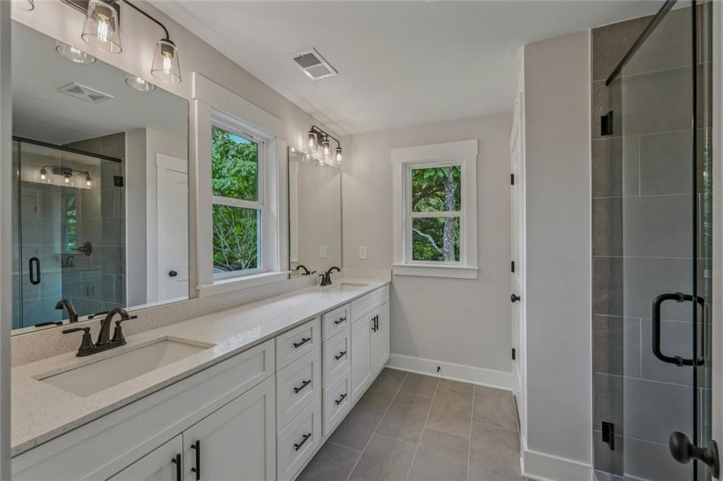 1179 Booker Avenue Southwest Atlanta, GA 30310 - Photo 32 of 54 a bathroom with a double vanity sink a mirror and a bathtub next to a window