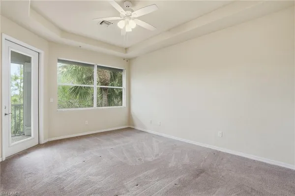an empty room with windows and fan