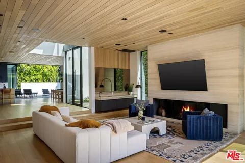 a living room with furniture a large window and wooden floors