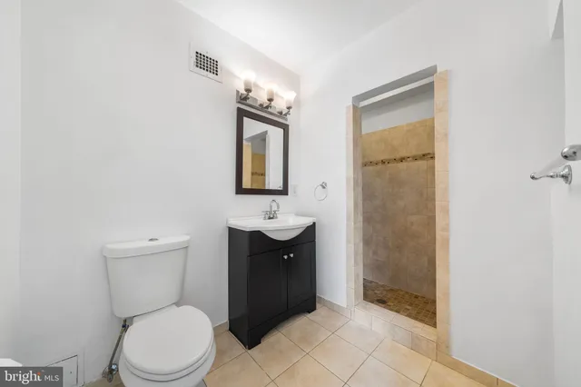 a bathroom with a toilet sink vanity and mirror
