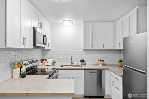 a kitchen with stainless steel appliances granite countertop a refrigerator sink and white cabinets