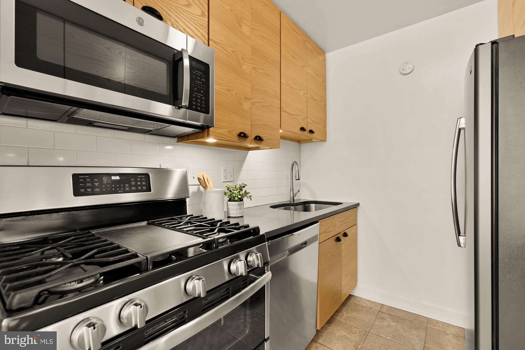 2400 41st Street Northwest, Unit 502 Washington, DC 20007 - Photo 12 of 25 a kitchen with stainless steel appliances granite countertop a stove and a microwave