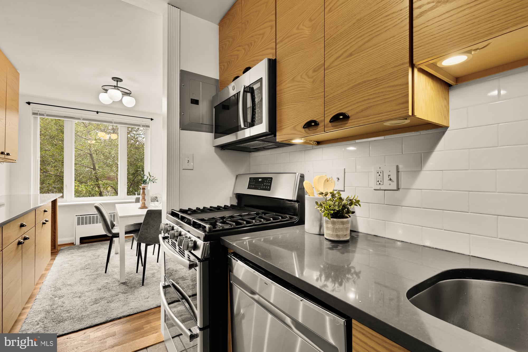 2400 41st Street Northwest, Unit 502 Washington, DC 20007 - Photo 13 of 25 a kitchen with stainless steel appliances granite countertop a sink a stove and wooden cabinets