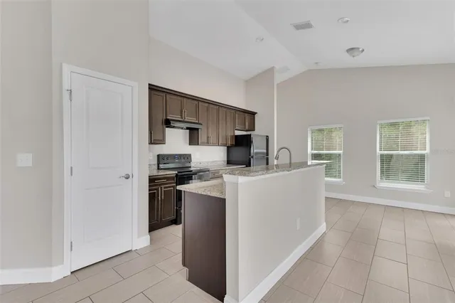 a living room with stainless steel appliances a refrigerator a sink a stove top oven a counter space and cabinets