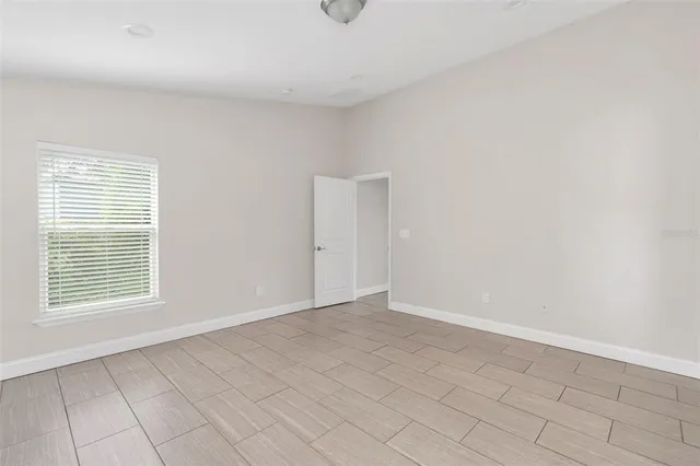 a view of an empty room with window and wooden floor