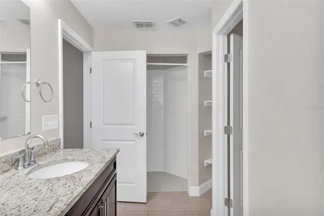 a en suite bathroom with a granite countertop sink and a mirror