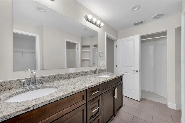 a bathroom with a granite countertop double vanity sink and a mirror