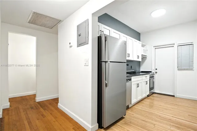 a kitchen with a refrigerator a stove top oven and wooden floor