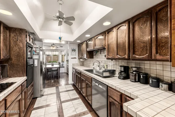 a kitchen with stainless steel appliances kitchen island granite countertop a refrigerator a sink dishwasher a stove and a dining table with wooden floor