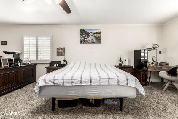 a bed sitting in a bedroom next to a window with pc on table and a large window