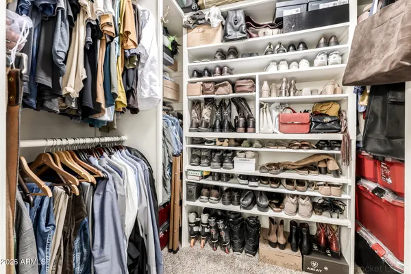 a view of walk in closet with clothes and shoes