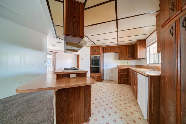 a kitchen with granite countertop a sink a stove top oven and cabinets