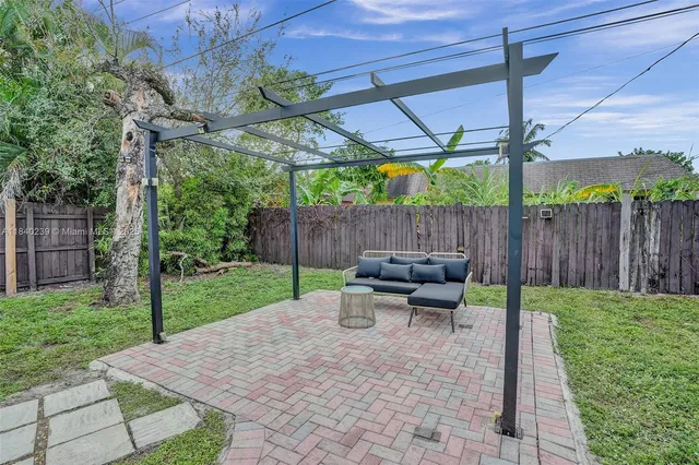 a view of a patio with table and chairs under an umbrella with a small yard