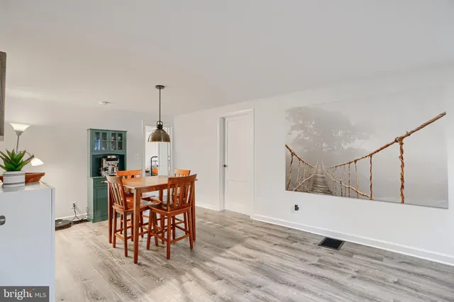 a view of a dining room and livingroom with furniture wooden floor a rug a painting and a chandelier