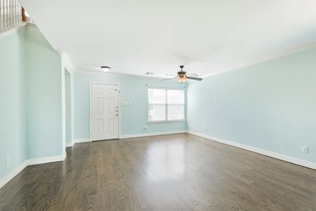 an empty room with wooden floor chandelier and windows