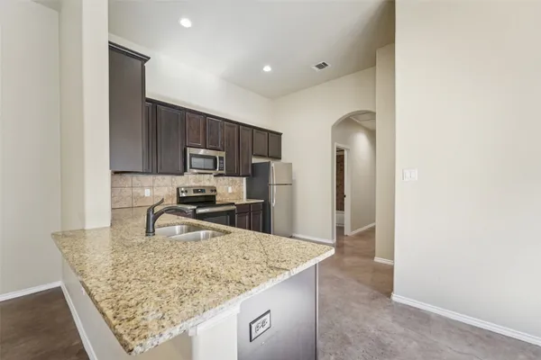 a kitchen with stainless steel appliances granite countertop a sink refrigerator and microwave