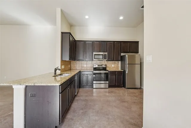 a kitchen with stainless steel appliances granite countertop a refrigerator a sink a stove a microwave and island