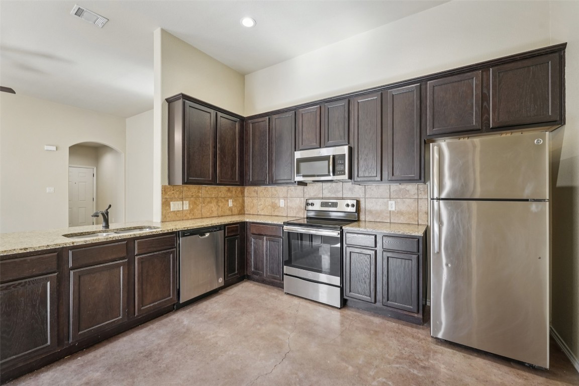 402 Jack Rabbit Lane, Unit B Buda, TX 78610 - Photo 13 of 30 a kitchen with stainless steel appliances granite countertop a refrigerator stove a sink and dishwasher