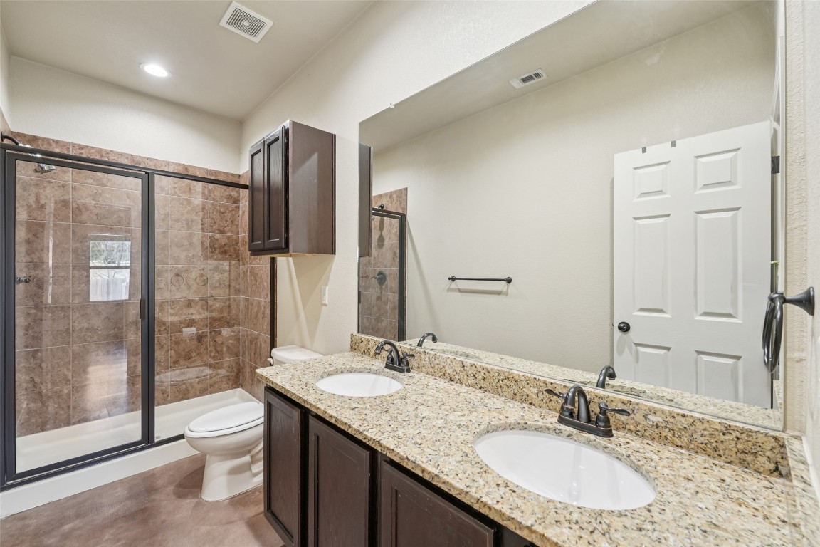 402 Jack Rabbit Lane, Unit B Buda, TX 78610 - Photo 25 of 30 a bathroom with a granite countertop sink toilet a large mirror a shower and a bathtub