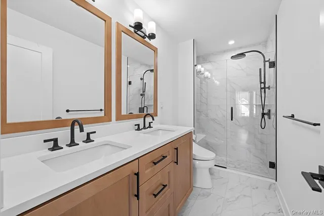 a bathroom with a shower sink vanity mirror and toilet