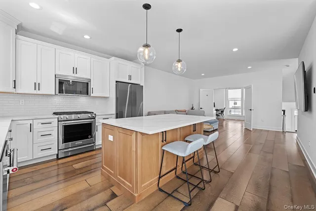 a kitchen with stainless steel appliances a stove a sink a refrigerator a center island and a stove