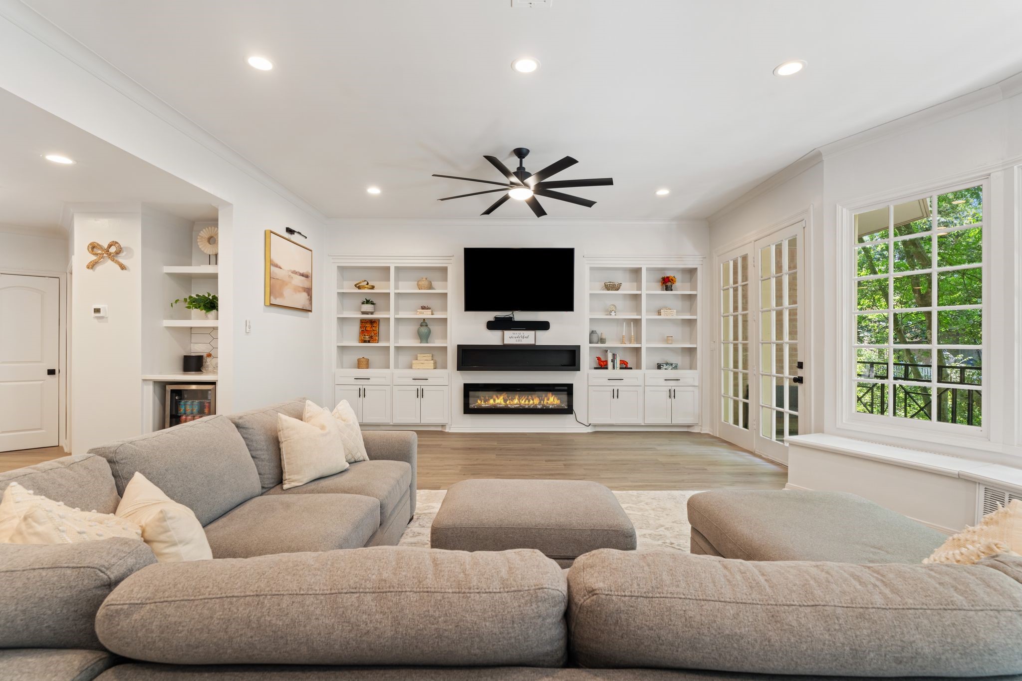 201 Vanderpool Lane, Unit 137 Houston, TX 77024 - Photo 13 of 42 Custom built-ins provide generous storage and display space along the living room wall, framing the sleek fireplace and creating a polished focal point. A large ceiling fan adds comfort and completes the room.