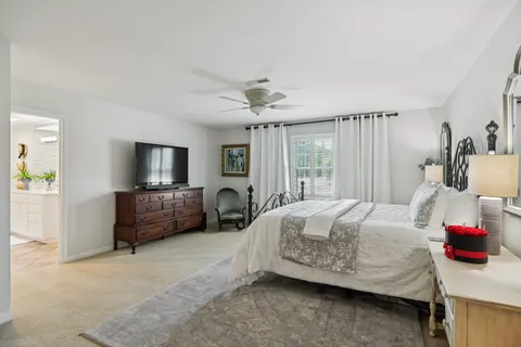 a bedroom with a bed a couch and a flat tv screen on dresser