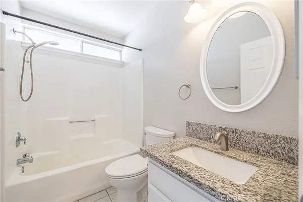 a bathroom with a granite countertop sink a toilet and a mirror