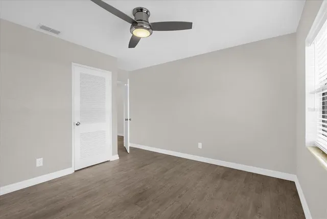 an empty room with a window and a fan