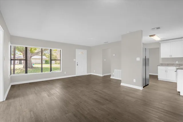 an empty room with wooden floor and windows