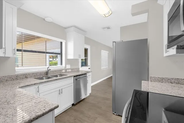 a kitchen with granite countertop sink window and refrigerator