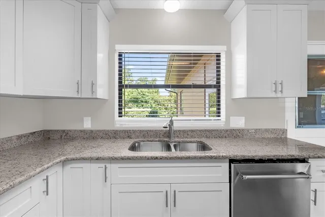 a kitchen with granite countertop white cabinets and a window