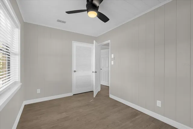 an empty room with windows and fan