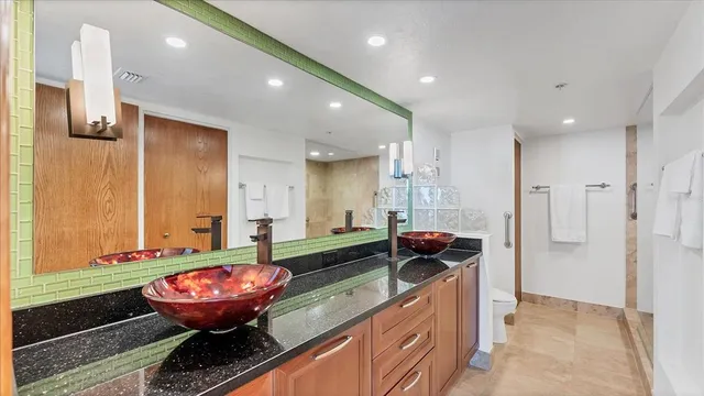 a bathroom with a granite countertop sink a toilet and a mirror
