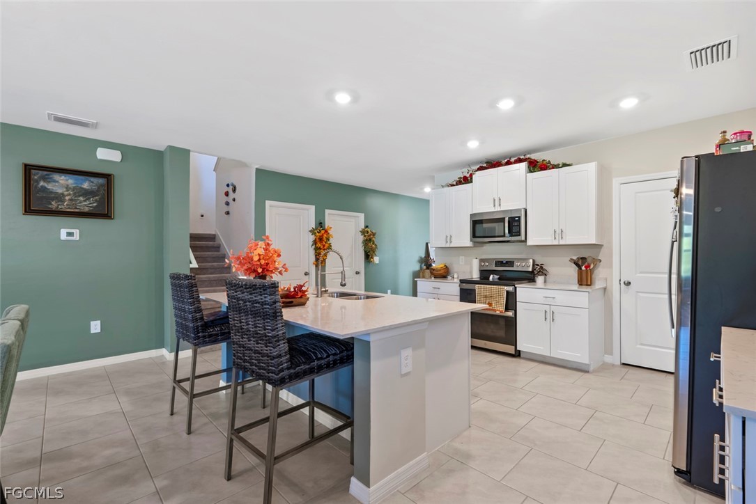 19972 Green Pasture Road Lehigh Acres, FL 33974 - Photo 11 of 48 a kitchen with white cabinets and stainless steel appliances