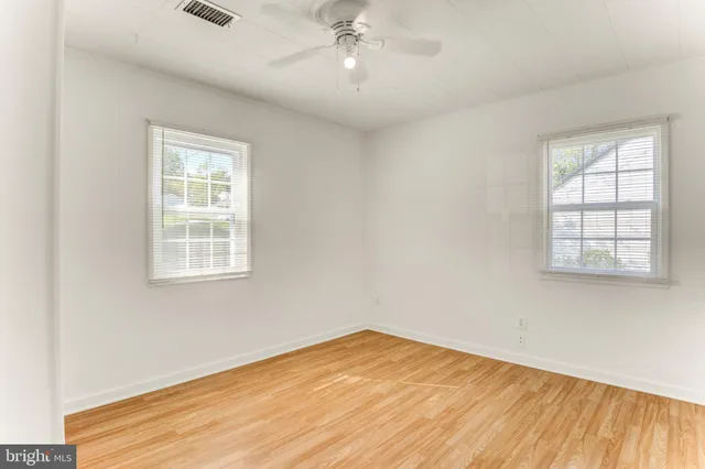 an empty room with wooden floor cabinet and windows