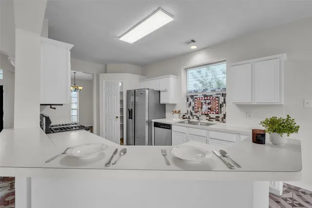 a kitchen with stainless steel appliances a white table chairs and a refrigerator