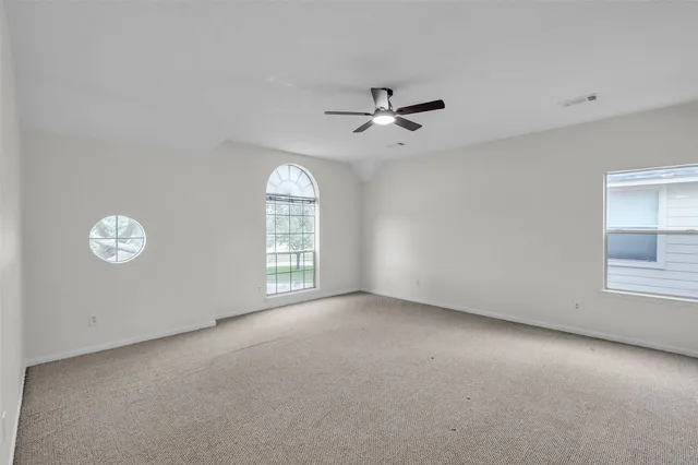 an empty room with windows and fan
