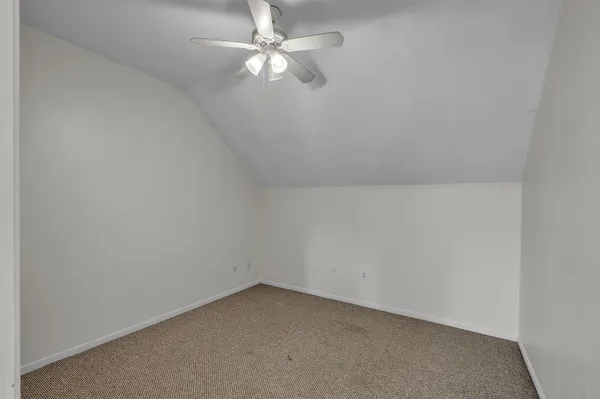 an empty room with a fan & a ceiling fan
