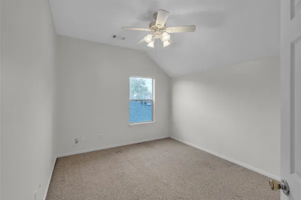 an empty room with a chandelier fan and windows