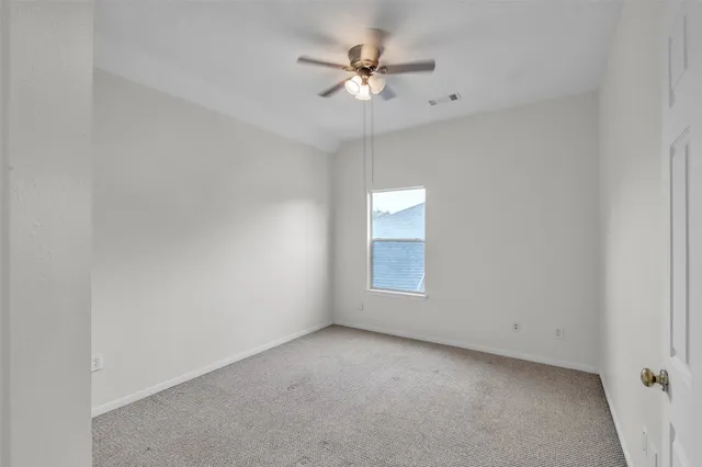 an empty room with a chandelier fan and windows