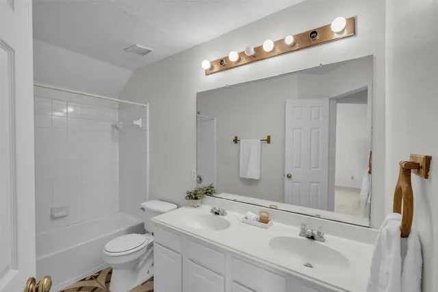 a bathroom with a sink double vanity mirror and a toilet