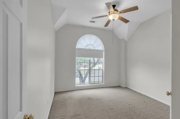 an empty room with a chandelier fan and windows