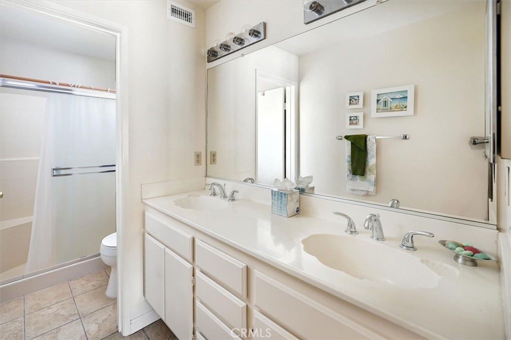 22713 Copper Hill Drive, Unit 42 Saugus, CA 91350 - Photo 24 of 32 a bathroom with double vanity sink a mirror and a toilet