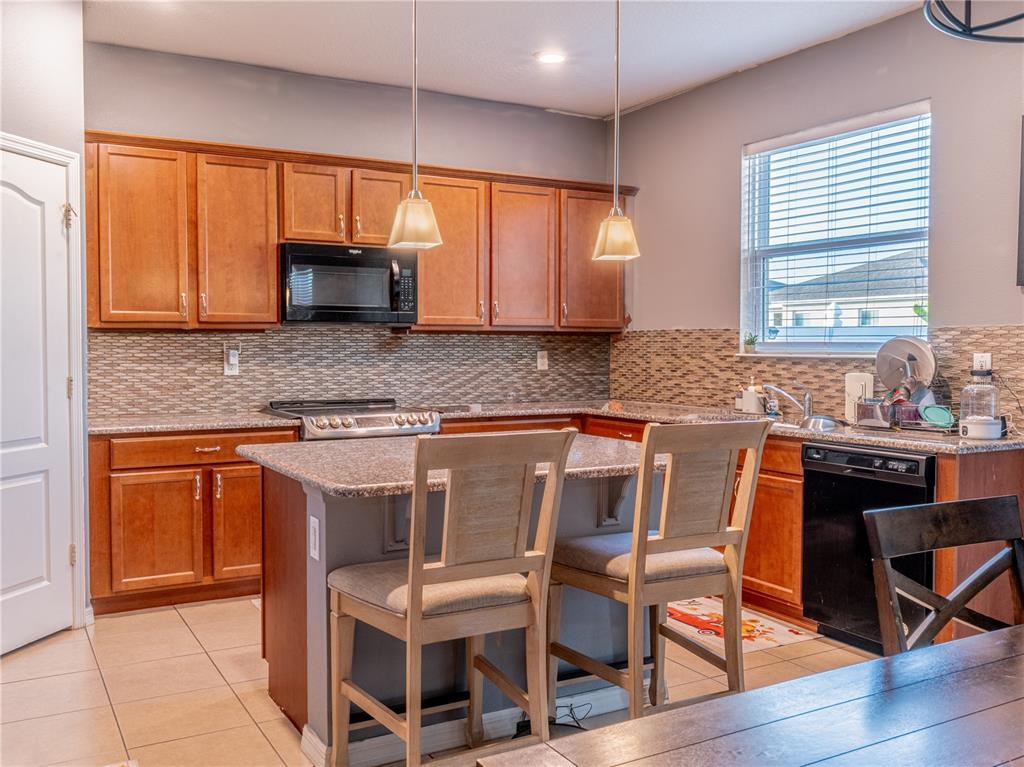 4504 Orchard Grove Road St. Cloud, FL 34772 - Photo 14 of 29 a kitchen with stainless steel appliances granite countertop a stove a sink and a microwave