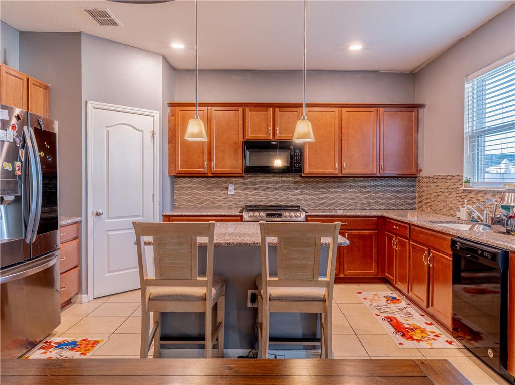 4504 Orchard Grove Road St. Cloud, FL 34772 - Photo 15 of 29 a kitchen with stainless steel appliances granite countertop a table chairs sink and cabinets